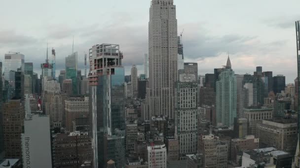 AEREO: Volare lungo l'Empire State Building a Manhattan circondato da falci nella trafficata città nella giornata nuvolosa — Video Stock