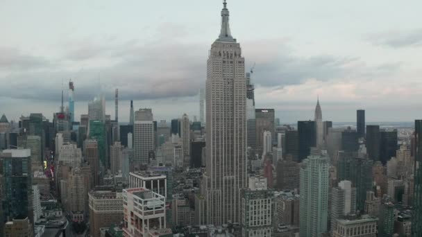AERIAL: Flying up the Empire State building in manhattan surrounded by scyscrapers in busy City at cloudy day — Stock Video