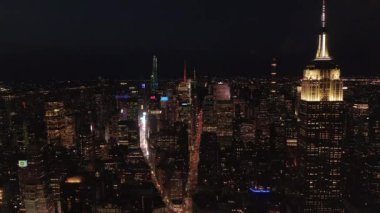Gökyüzündeki ikonik Empire State Binası gece yarısı Manhattan, New York 'taki paralel caddeleri ve kavşakları aydınlattı.