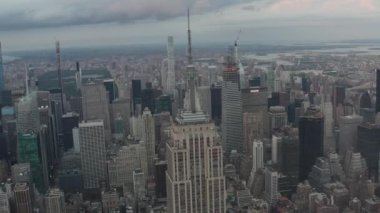 Manhattan 'daki Empire State binasının üzerinde bulutlu bir günde kalabalık şehirde tırpanlarla çevrili destansı bir manzara var. 