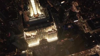 Gökyüzündeki ikonik Empire State Binası üzerinde nefes kesici bir uçuş paralel caddeler ve kavşakları aydınlattı Manhattan, New York 'ta gece yarısı konut ve ofis binaları.