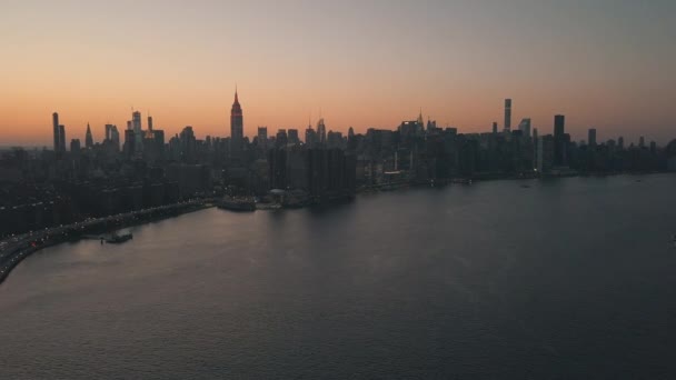 AERIAL: Over East River s výhledem na Manhattan New York City panorama v krásné svítání západ slunce oranžové světlo — Stock video