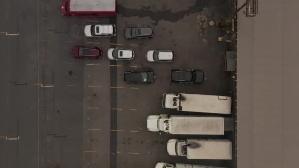 AERIAL: Birdseye Zicht op Vrachtwagen parkeren in laadruimte met kratten en containers en de man stapt uit witte vrachtwagen — Stockvideo