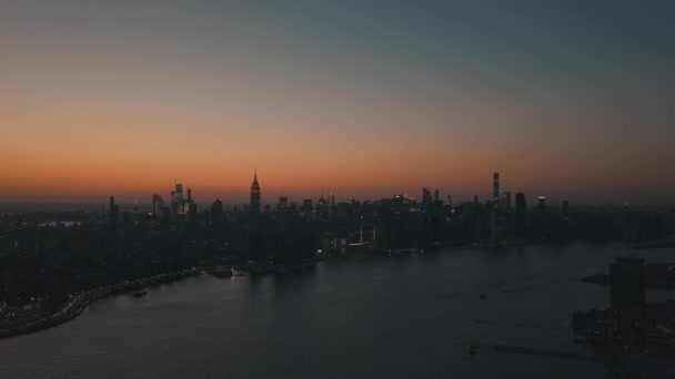 AERIAL: Över East River visar Manhattan New York City Skyline i Beautiful Dawn Sunset Orange Light strax före Dark — Stockvideo