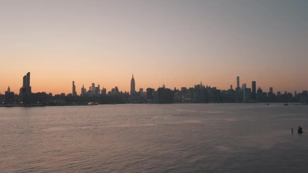 AERIAL: 아름다운 새벽 선셋 오렌지 빛의 맨하탄 시 스카이라인이 내려다 보이는 이스트 강을 횡단하는 모습 — 비디오