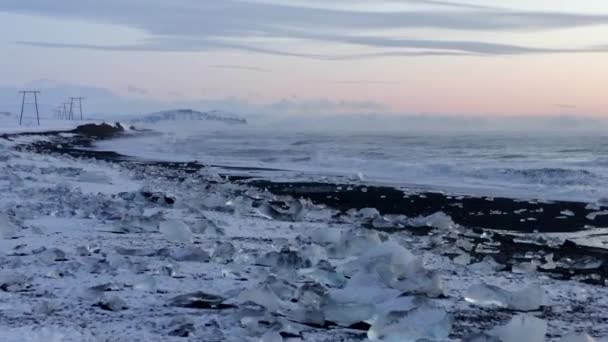 AERIAL: Vliegen over Diamond Beach, Black Beach in IJsland in de winter Sneeuw, IJs, Golven, Water — Stockvideo