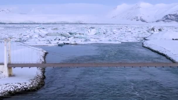 AÉRIAL : Survoler le pont en voiture en direction des flots de glace enneigés sur le lac Islande Hiver, Neige 