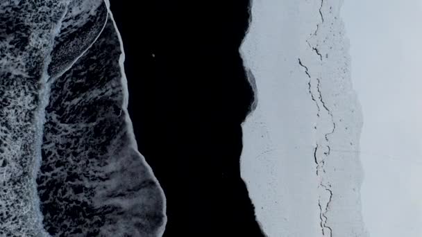 AERIAL: Birdsview of Black Beach with white arctic snow in Iceland in Winter Nieve, hielo, olas, agua — Vídeo de stock