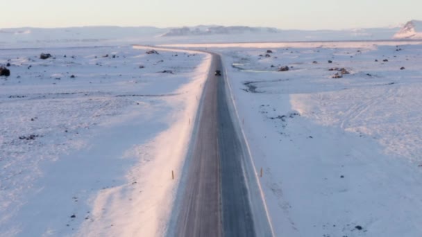 AERIAL: Sneeuwwitje landschap met weg na Jeep in IJsland bij zonsondergang Winter, Zon, Arctische — Stockvideo