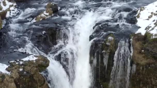 AERIAL: Över vattenfall i snö, Ice Canyon på Island grönt gräs, molnigt — Stockvideo