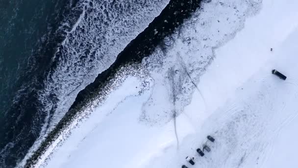 AERIAL: Pohled na Černou pláž s bílým arktickým sněhem na Islandu v zimním sněhu, ledu, vln, vody — Stock video
