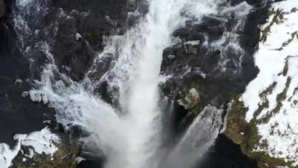 AERIAL: Närbild av vattenfall i snö, Ice Canyon på Island flyger uppåt grönt gräs, molnigt — Stockvideo