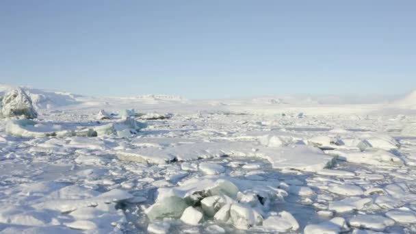 AERIAL: Vliegen over wit, Blauw Bobbie ijs drijft op IJsland Lake Winter, Sneeuw — Stockvideo
