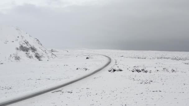 AERIAL: Sobre a paisagem branca da neve com estrada, montanha em Islândia Inverno, nevar, frio, Ártico — Vídeo de Stock