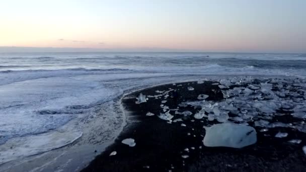 AERIAL: Vliegen over Diamond Beach, Black Beach in IJsland in de winter Sneeuw, IJs, Golven, Water — Stockvideo