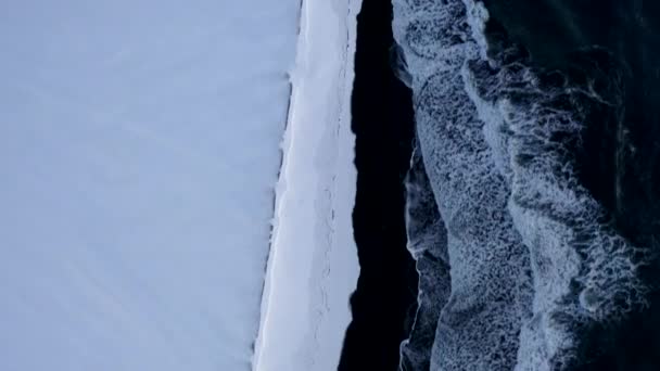 AERIAL: Vista sobre Playa Negra con nieve blanca ártica Montañas, Paisaje en Islandia en invierno Nieve, Hielo, Olas, Agua — Vídeos de Stock