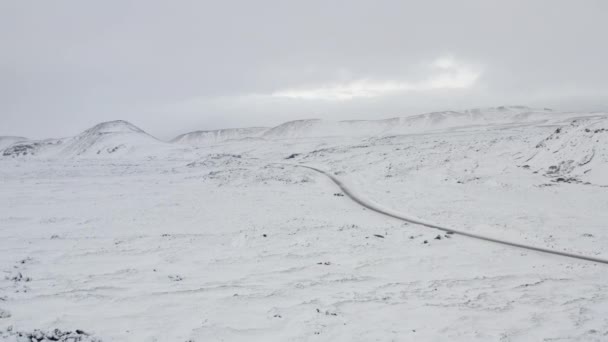 AERIAL: Přes sněhobílou krajinu se silnicí, Hory na Islandu Zima, Sníh, Studená, Arktida — Stock video