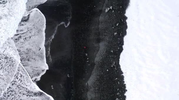 특별: 북쪽 눈, 얼음, 파도, 물, 아이슬란드의 흰 눈 과 함께 검은 해변을 거닐고 있는 사람을 위에서 내려다보는 사람 — 비디오