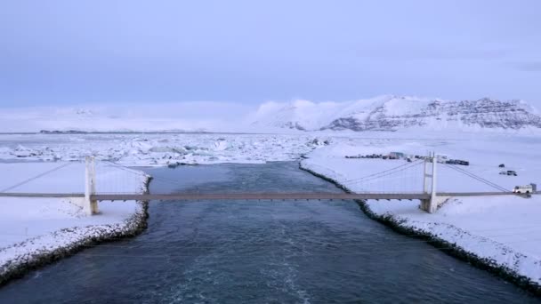 AERIAL: Flying over Bridge with Car driving over towards Snowy Ice Floes on Iceland Lake Winter, Snow — Stock Video