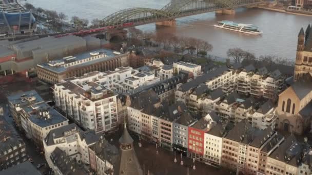 AERIAL: Přes Kolín nad Rýnem Staré město a pohled na Rýn a Hohenzollern most s vlakovým přejezdem a loď projíždějící na slunný den — Stock video