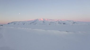 Pembe güneş ışığıyla kar beyazı dağı İzlanda 'da kışın zirveye vuruyor.