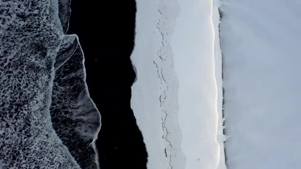 AERIAL: Pohled na Černou pláž s bílým arktickým sněhem na Islandu v zimním sněhu, ledu, vln, vody — Stock video