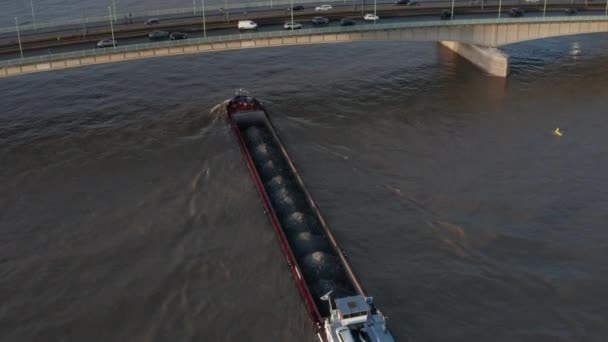 AERIAL: Vista sobre o rio Reno em Colônia Barco de carga passando sob uma ponte na bela luz do sol — Vídeo de Stock