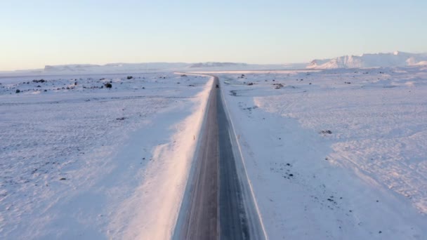 AERIAL: Paisagem Branca de Neve com Estrada seguindo Jeep na Islândia ao pôr do sol Inverno, Sol, Árctico — Vídeo de Stock