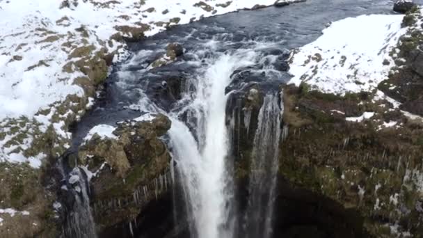 AERIAL: Nad wodospadem w śniegu, Kanion lodowy na Islandii Zielona trawa, Chmury — Wideo stockowe