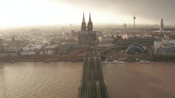 AERIAL: Blick über die Kölner Hohenzollernbrücke und Blick auf Dom und Fernsehturm im nebligen Sonnenlicht 
