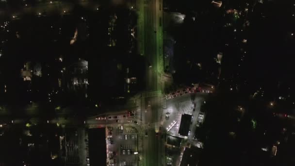 АЭРИАЛ: вид на улицу в ночное время с парковочным местом в магазине и городскими светофорами — стоковое видео
