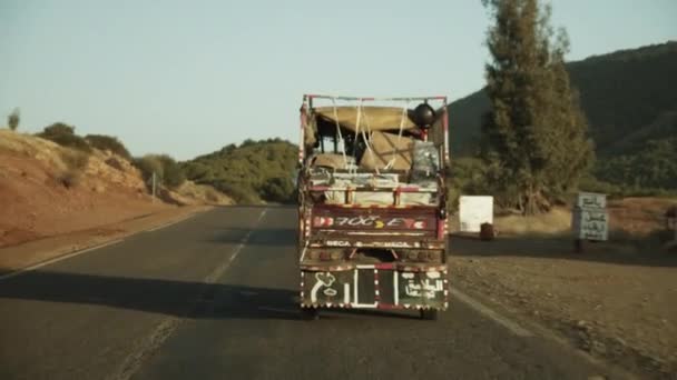 重い積載された古いトラックは、晴れた日にアフリカの野生を通って運転します — ストック動画