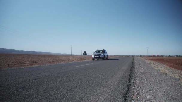 Медленное движение: SILVER SUV CAR CRUISING OVER HIGHWAY TROUGH DESERT IN MOROCCO SUNNY DAY — стоковое видео