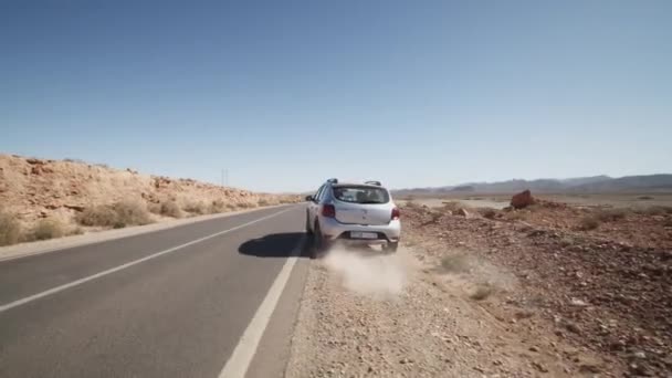 ZILVER SUV AUTO DRIVING OVER DE DESERT ROAD OP ZONNY DAG — Stockvideo