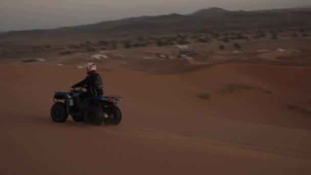 MOVIMIENTO Lento: ATV QUAD CONDUCIENDO DUNE EN EL DESERTO DE SAHARA A LA LUZ DEL SOL — Vídeo de stock