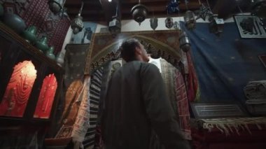 Fas 'ın eski bir kasabasındaki eski püskü arabalarla eski bir dükkâna doğru yürüyen genç bir adam. 