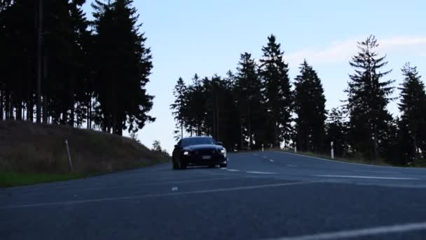 Carro preto de Ford Mustang que conduz fora na montanha, estrada da floresta com estrada da luz do sol, carro do músculo — Vídeo de Stock