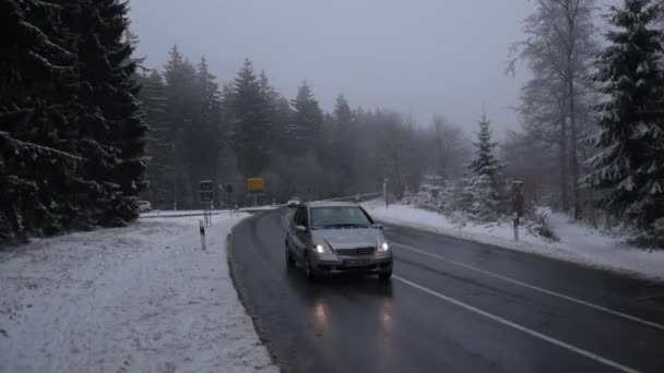 Auto fährt auf verschneiter Straße bei Wald in Frankfurt am Main (Taunus) vorbei — Stockvideo