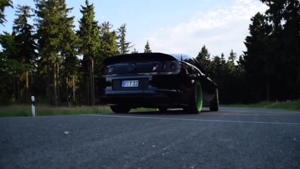 Schwarzer Ford Mustang Auto fährt auf Berg, Waldstraße mit Sonnenschein Straße, Muscle Car — Stockvideo