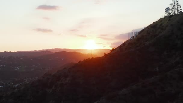 AERIAL: Hollywood Hills im wunderschönen Sonnenuntergang Goldene Stunde Licht und Blick auf Hollywood Zeichen auf der Bergseite in Los Angeles, Kalifornien — Stockvideo