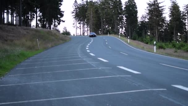 黑色福特野马车在山上开过，林荫道有阳光路，肌肉车 — 图库视频影像