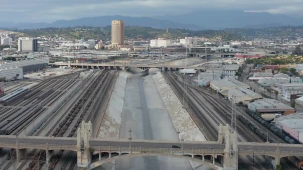 AERIAL: Río Los Ángeles con agua en el cielo nublado nublado junto a las vías de tren — Vídeos de Stock