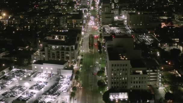 AERIAL: Lot nad Wilshire Boulevard Street w Hollywood Los Angeles nocą z widokiem na ulice i miejskie światła samochodowe — Wideo stockowe