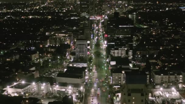 AERIAL: Vuelo sobre Wilshire Boulevard Street en Hollywood Los Ángeles por la noche con vista a las calles y los semáforos de coches urbanos — Vídeo de stock
