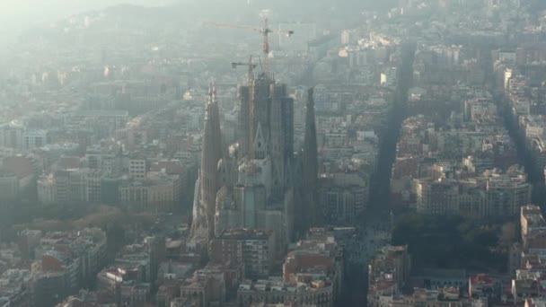 AERIAL: Hacia La Sagrada Familia con grúas en la hermosa ciudad Sunny Haze sobre Barcelona, España — Vídeos de Stock