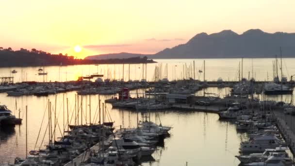 AERIAL: Porto sull'isola tropicale con barche a vela e oceano a piccola città all'alba con montagne sullo sfondo Vacanza, Viaggi, Tramonto — Video Stock