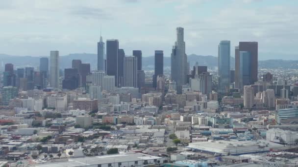AERIAL: Lento plano lateral del centro de Los Ángeles Skyline con Warehouse Art Distrct en primer plano con cielo azul y nubes — Vídeos de Stock