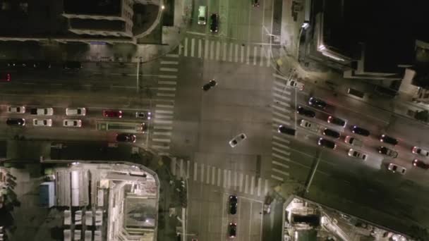 AERIAL: Aumento de la sobrecarga en la calle de la intersección con el sitio grande de la construcción y agujeros en tierra en la noche con las calles que brillan y los semáforos del coche de la ciudad — Vídeo de stock