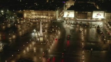 Paris 'teki Place de la Concorde üzerinden gece uçuşu Islak Zemin ve Parlak Şehir ışıklarıyla 
