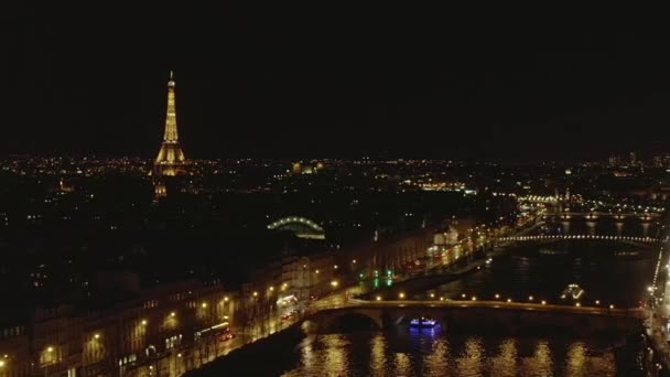 АЭРИАЛ: Вид на реку Мбаппе ночью в Париже, Франция с видом на Эйфелеву башню, свет Эйфелевой башни и городские огни — стоковое видео